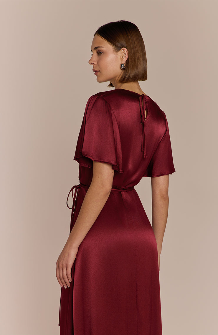 Woman wearing a burgundy satin dress against a beige background