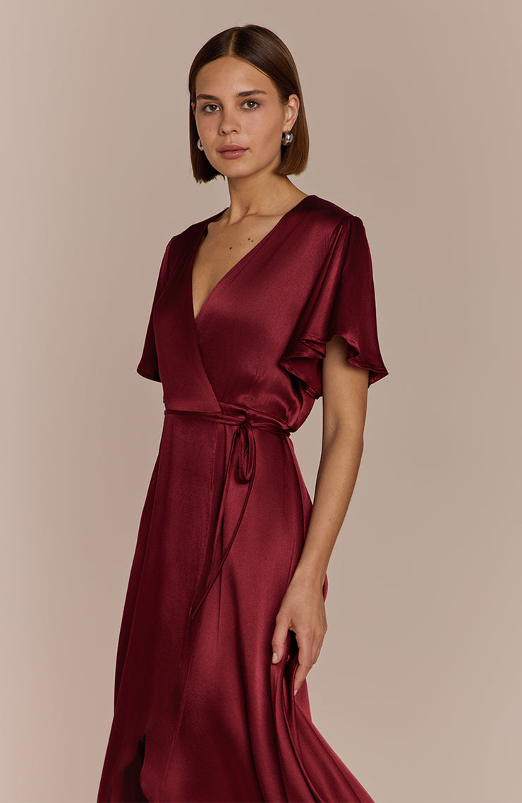 Woman wearing a burgundy satin dress against a beige background