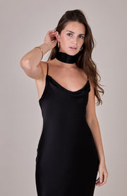Woman wearing a black slip dress against a plain background