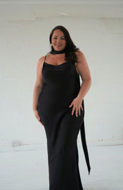 Woman wearing a black slip dress against a white background