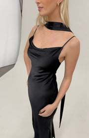 Woman wearing a black satin dress against a neutral background