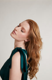 Woman with long, wavy hair wearing a green top against a plain background