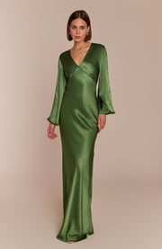 Woman wearing a green satin gown against a beige background