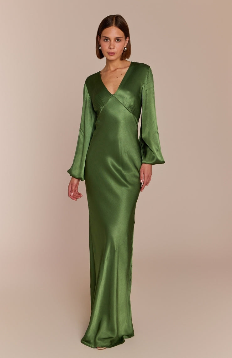 Woman wearing a green satin gown against a beige background