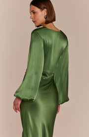 Green satin dress with long sleeves on a beige background