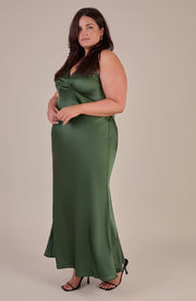 Woman wearing a green satin dress against a beige background