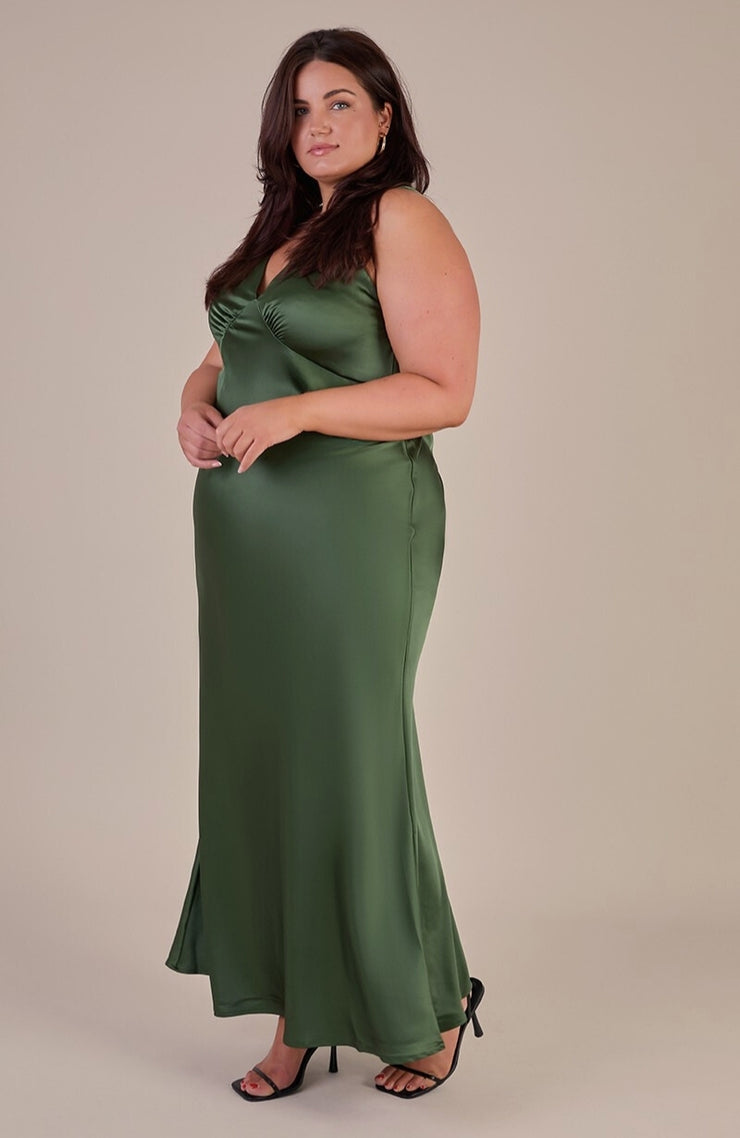 Woman wearing a green satin dress against a beige background