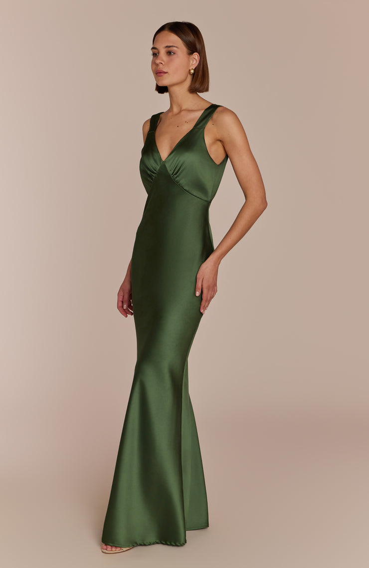 Woman wearing a green satin gown against a beige background