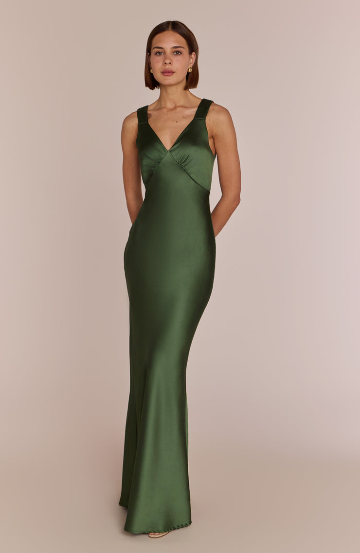 Woman wearing a green evening gown against a beige background