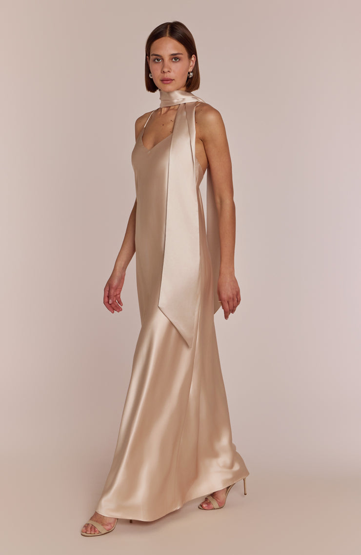 Woman wearing a beige evening gown against a plain background