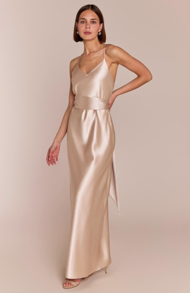 Woman wearing a gold evening gown against a beige background