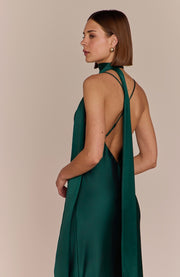 Woman wearing a green halter neck dress with a beige background