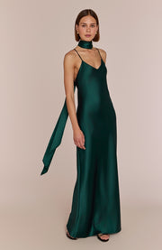 Woman wearing a green satin gown with a plain background