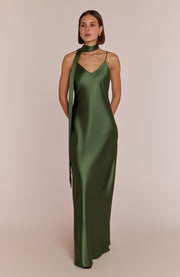 Woman wearing a green satin dress with a plain background