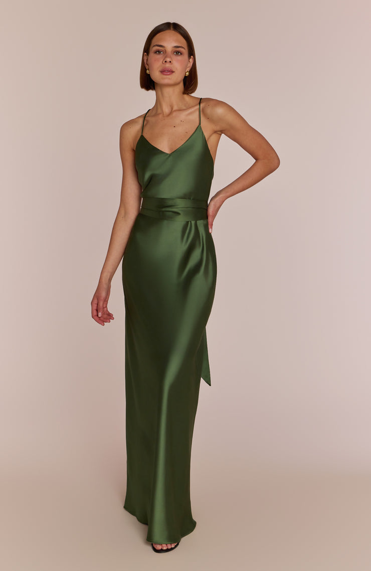 Woman wearing a green satin dress against a beige background