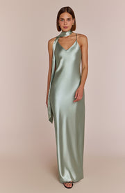 Woman wearing a long green dress with a plain background