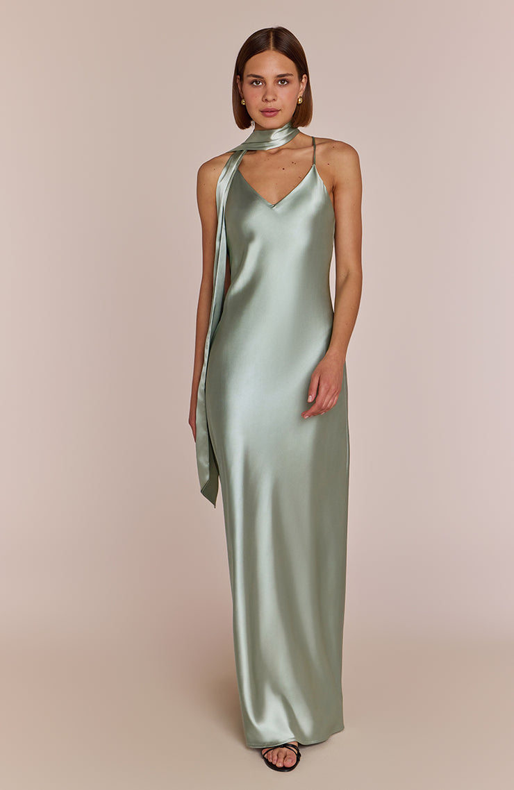 Woman wearing a long green dress with a plain background
