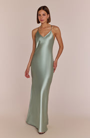 Woman wearing a green satin slip dress against a beige background
