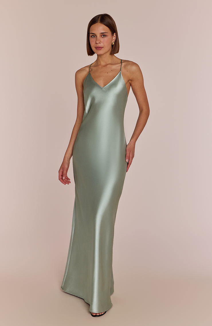 Woman wearing a green satin slip dress against a beige background