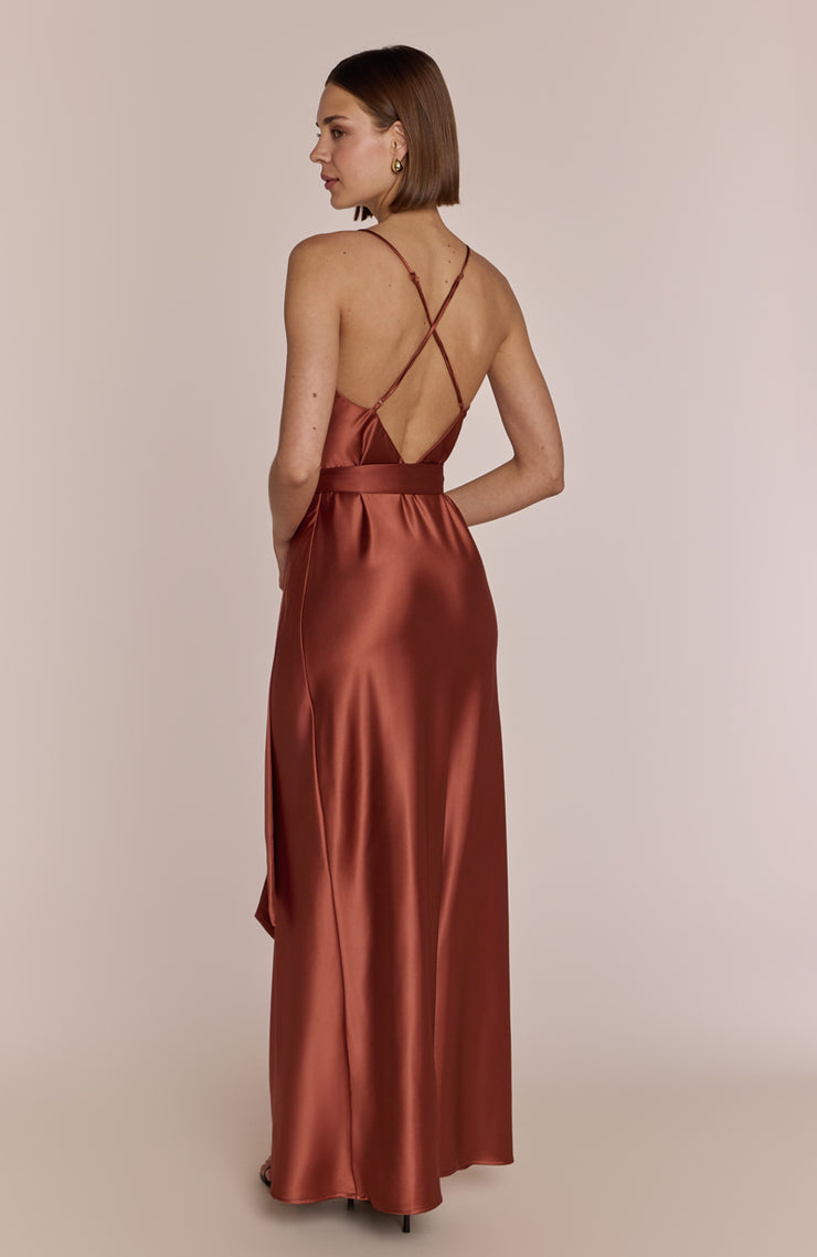 Woman wearing a rust-colored satin dress with a backless design on a beige background