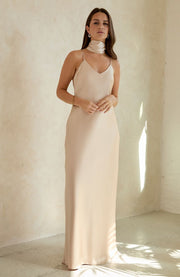 Woman wearing a beige slip dress against a plain background