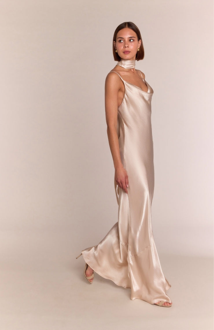 Woman wearing a long satin dress against a plain background