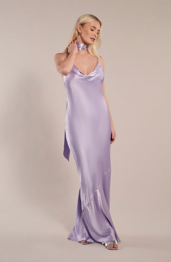 Woman wearing a lavender satin slip dress against a plain background