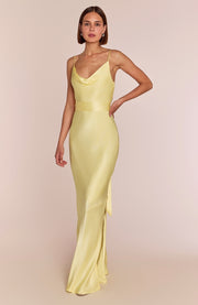 Woman wearing a light yellow evening gown against a beige background