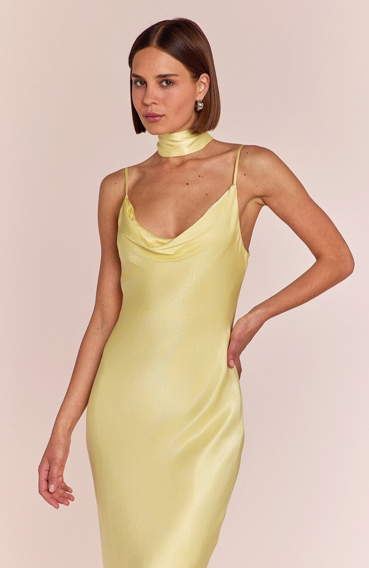 Woman wearing a light yellow satin dress against a beige background