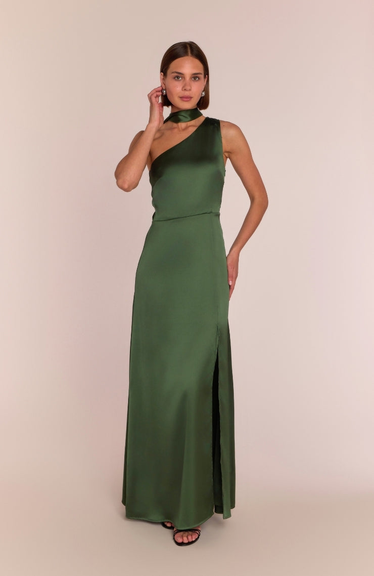 Woman wearing a green one-shoulder dress with a slit on a beige background