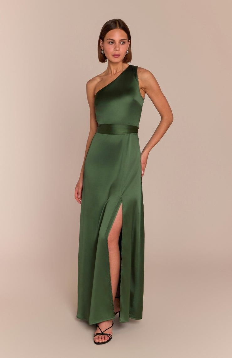 Woman wearing a green one-shoulder dress with a slit on a beige background