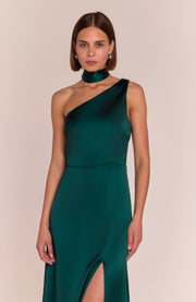 Woman wearing a green one-shoulder dress with a slit on a beige background