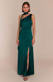 Woman wearing a green evening gown with a slit on a beige background