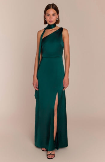 Woman wearing a green evening gown with a slit on a beige background