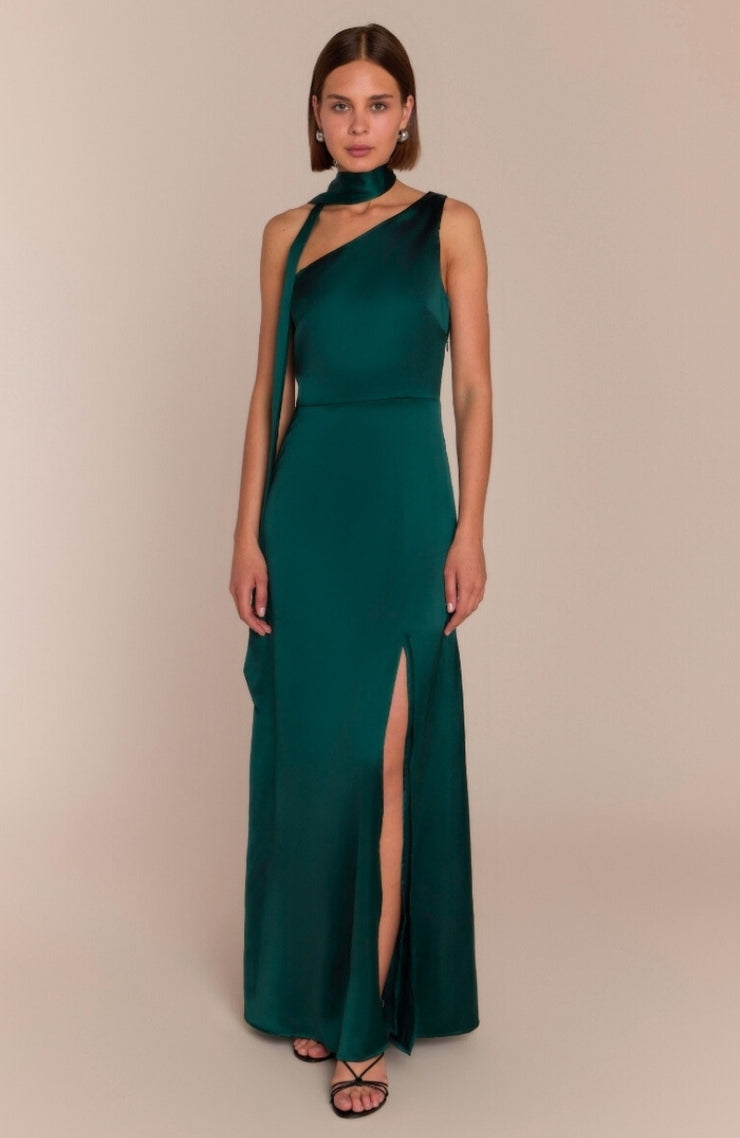 Woman wearing a green evening gown with a slit on a beige background