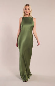 Woman wearing a green satin dress against a beige background