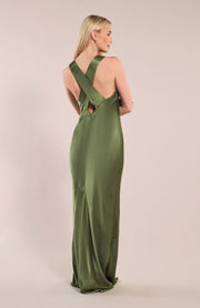 Woman wearing a green evening gown with cut-out back design on a beige background