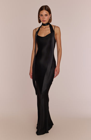 Woman wearing a black dress with sheer panels on a beige background