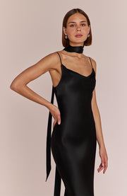 Woman wearing a black slip dress against a neutral background