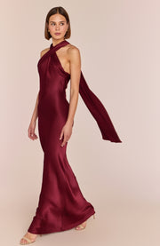 Woman wearing a burgundy halter neck gown on a beige background