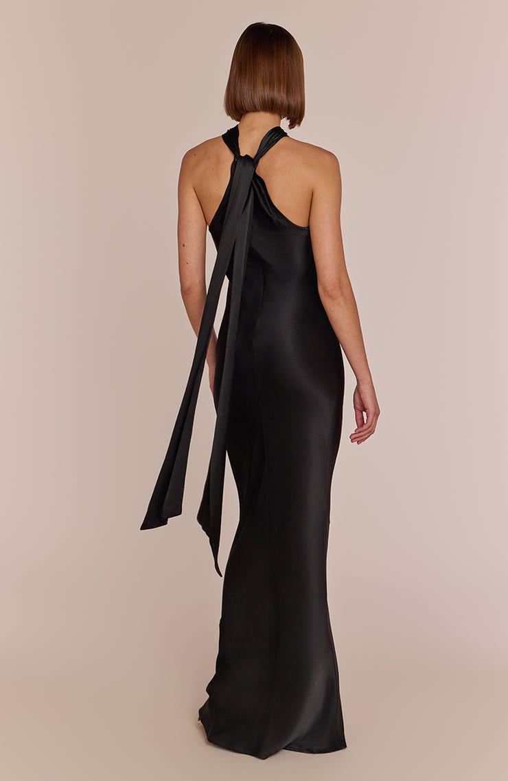 Woman wearing a black evening gown with a large bow detail on a beige background