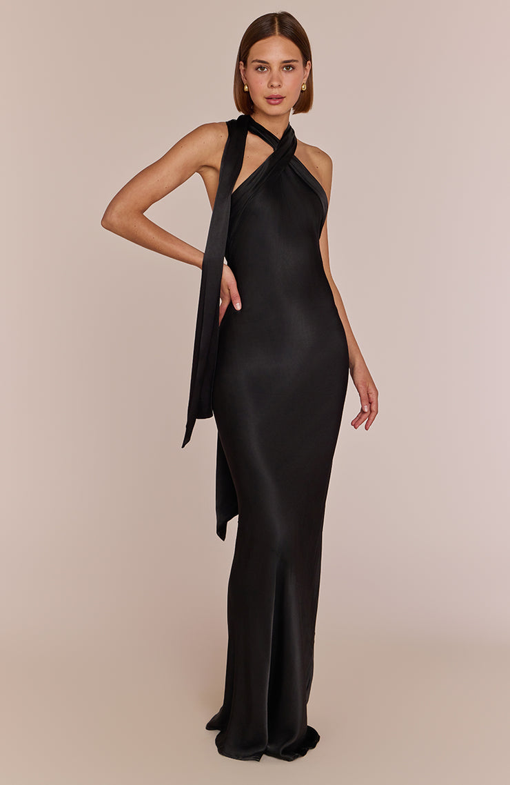 Woman wearing a black evening gown with a long train on a beige background