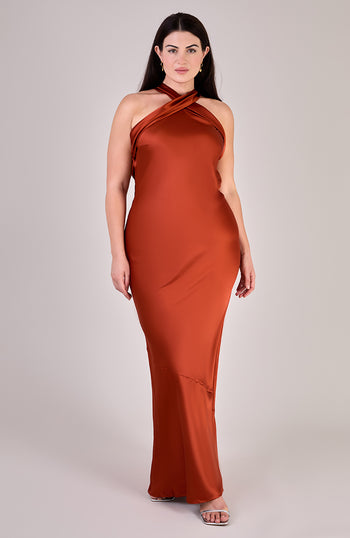 Woman wearing a rust-colored halter neck dress on a plain background
