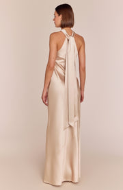 Woman wearing a beige halter neck gown on a plain background