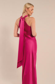 Woman wearing a pink satin gown with a long train against a beige background