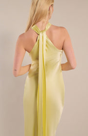 Yellow halter neck dress with a long train on a beige background
