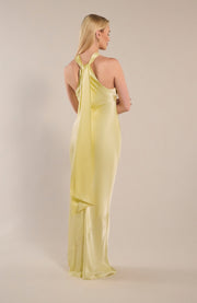 Woman wearing a light yellow halter neck dress against a plain background