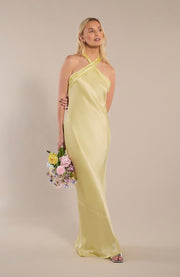 Woman in a yellow dress holding flowers against a beige background