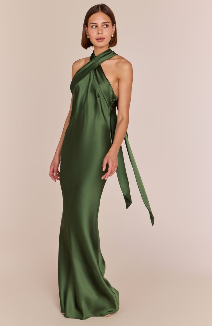 Woman wearing a green satin halter neck gown on a beige background