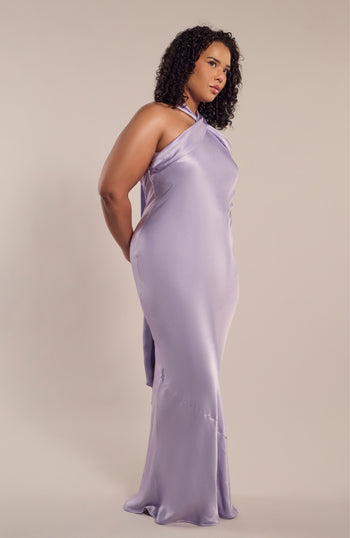 Woman wearing a lavender one-shoulder dress against a plain background